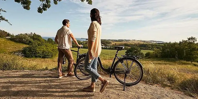 A man and a woman are standing next to bicycles outside.