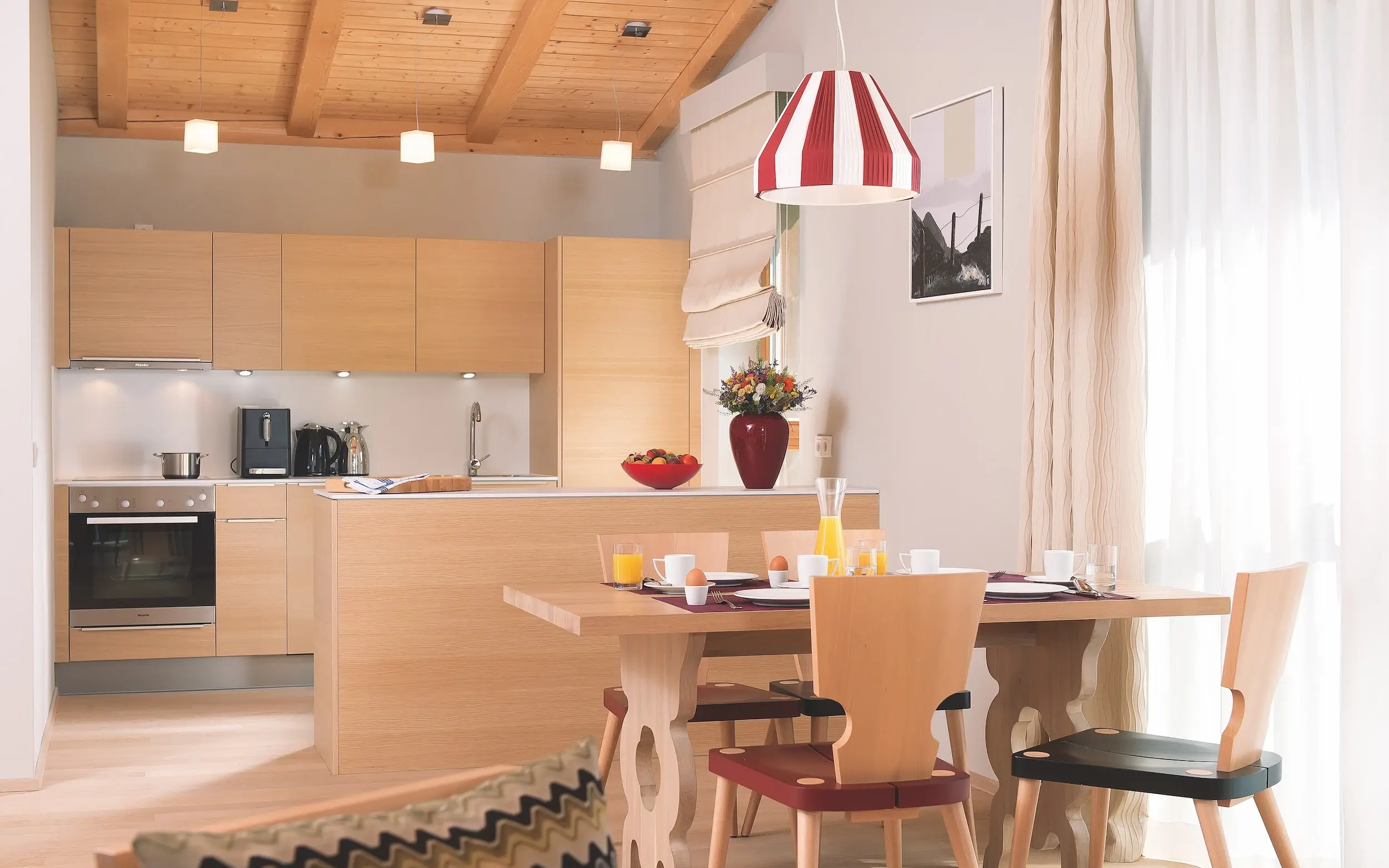 Modern kitchen with table and chairs, built-in cupboards and kitchen appliances.