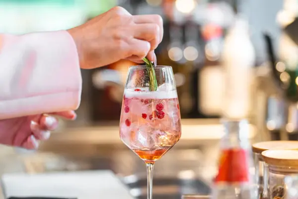 Eine Person legt ein Blatt auf ein Getränk in einem Glas.
