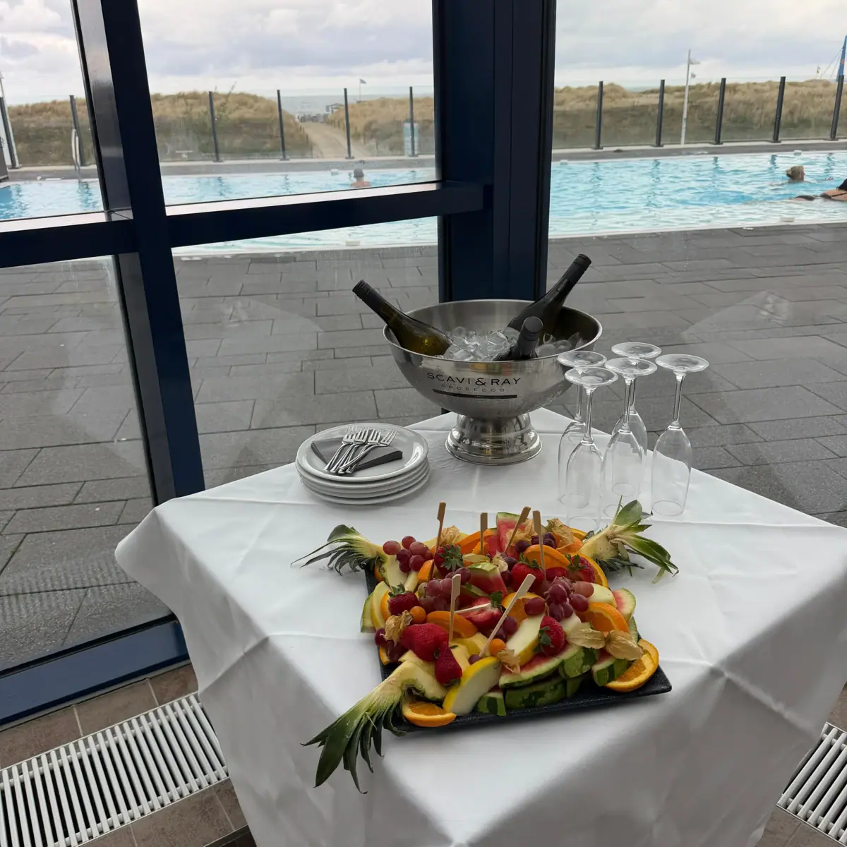 Ein Tisch mit einer Schale Wein und Obst darauf.