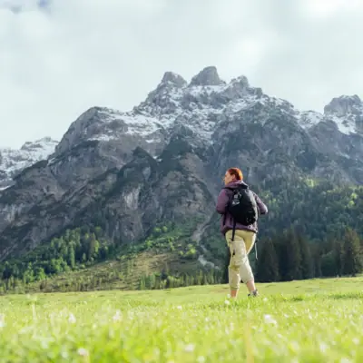 Eine Frau steht in einem Feld mit Bergen im Hintergrund.