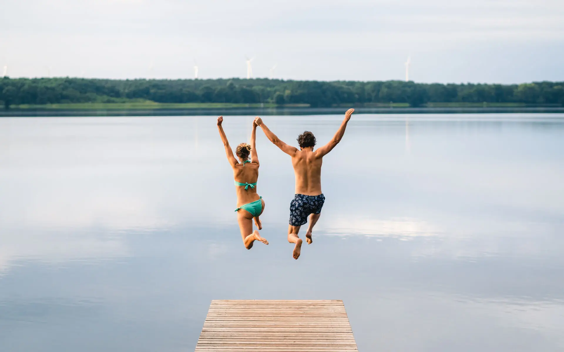 Ein Mann und eine Frau springen in einen See.