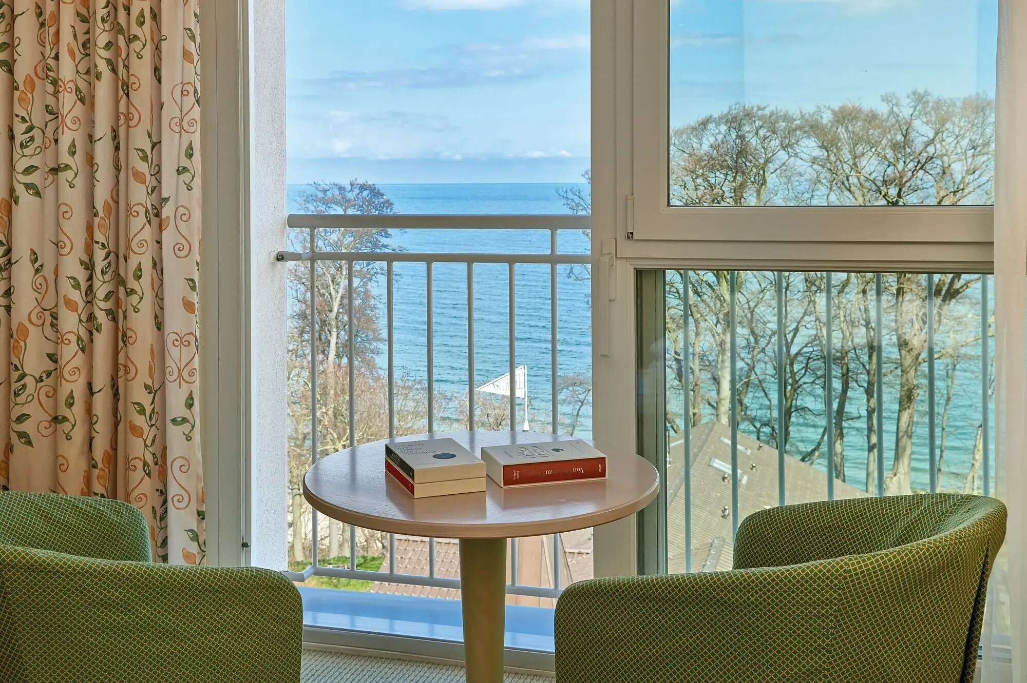 Ein Tisch mit Büchern darauf, neben einem Balkon mit Blick auf das Meer.