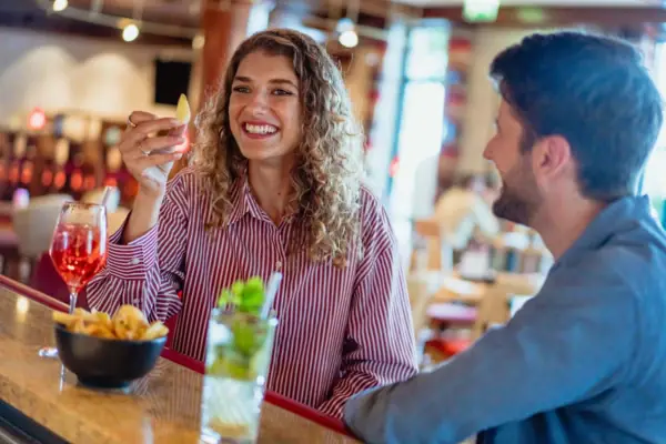 Bar Eine Frau hält ein Stück Obst, während ein Mann an einer Bar sitzt.