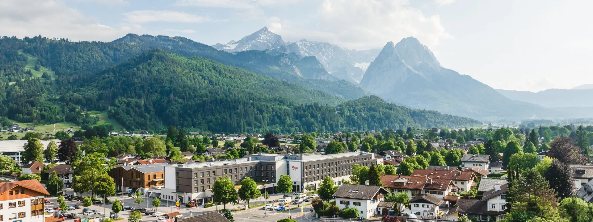 Eine Stadt mit vielen Gebäuden und Bäumen, im Hintergrund Berge.