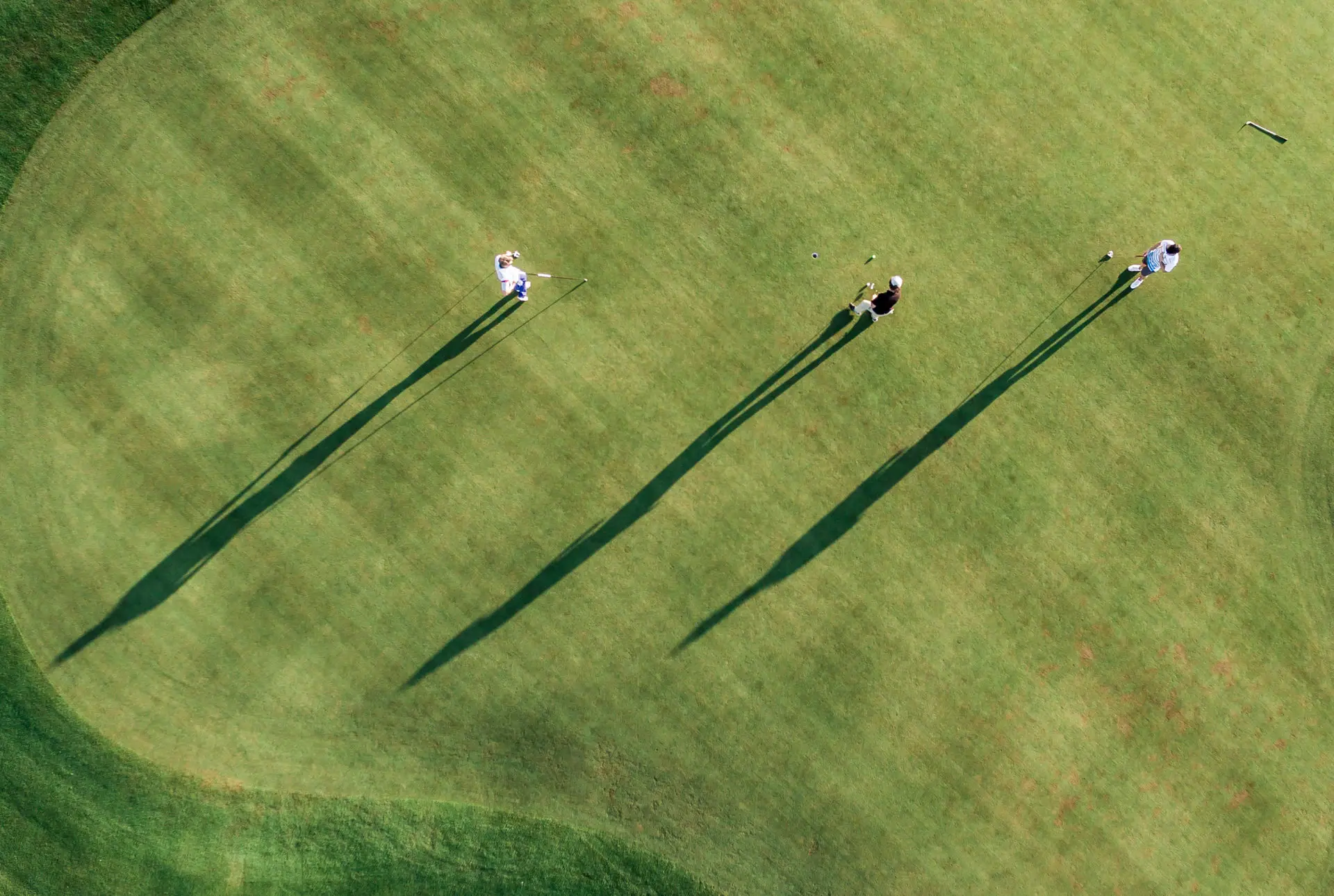 Eine Gruppe von Menschen spielt Golf auf einem Rasen.