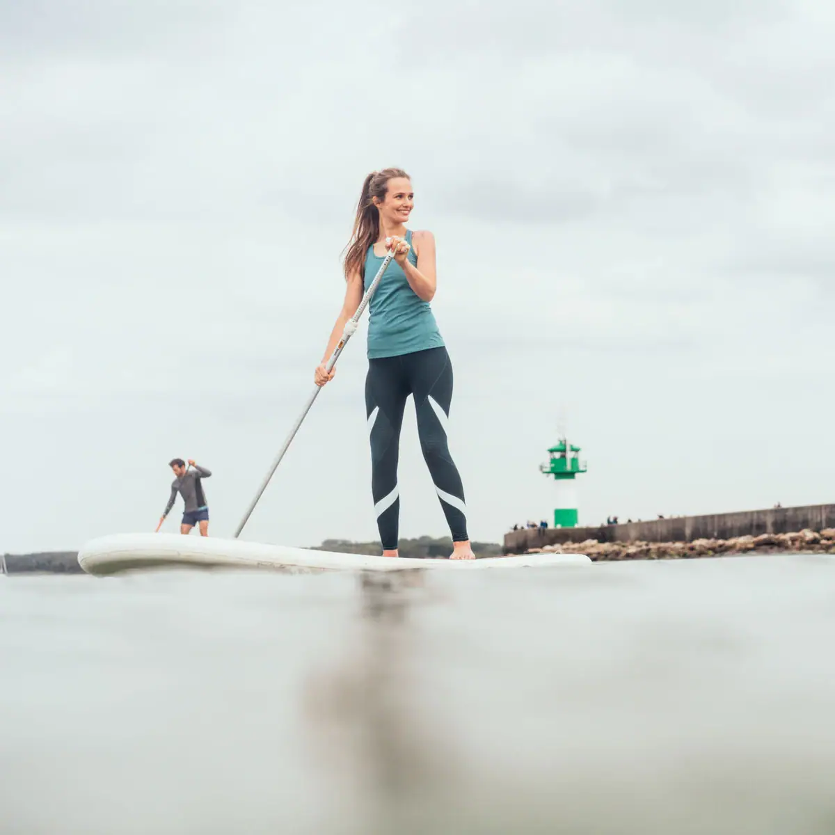 Eine Frau und ein Mann auf einem Surfbrett auf dem Wasser.
