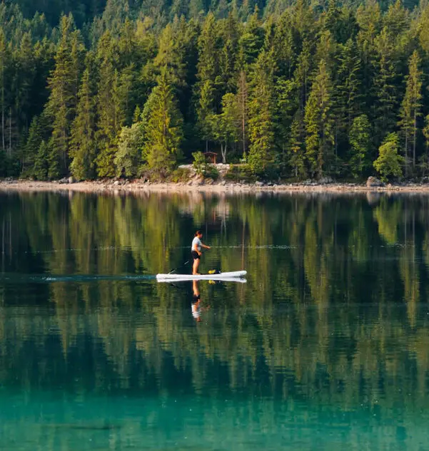 Ein Mensch auf dem Eibsee mit einem stand up paddle board