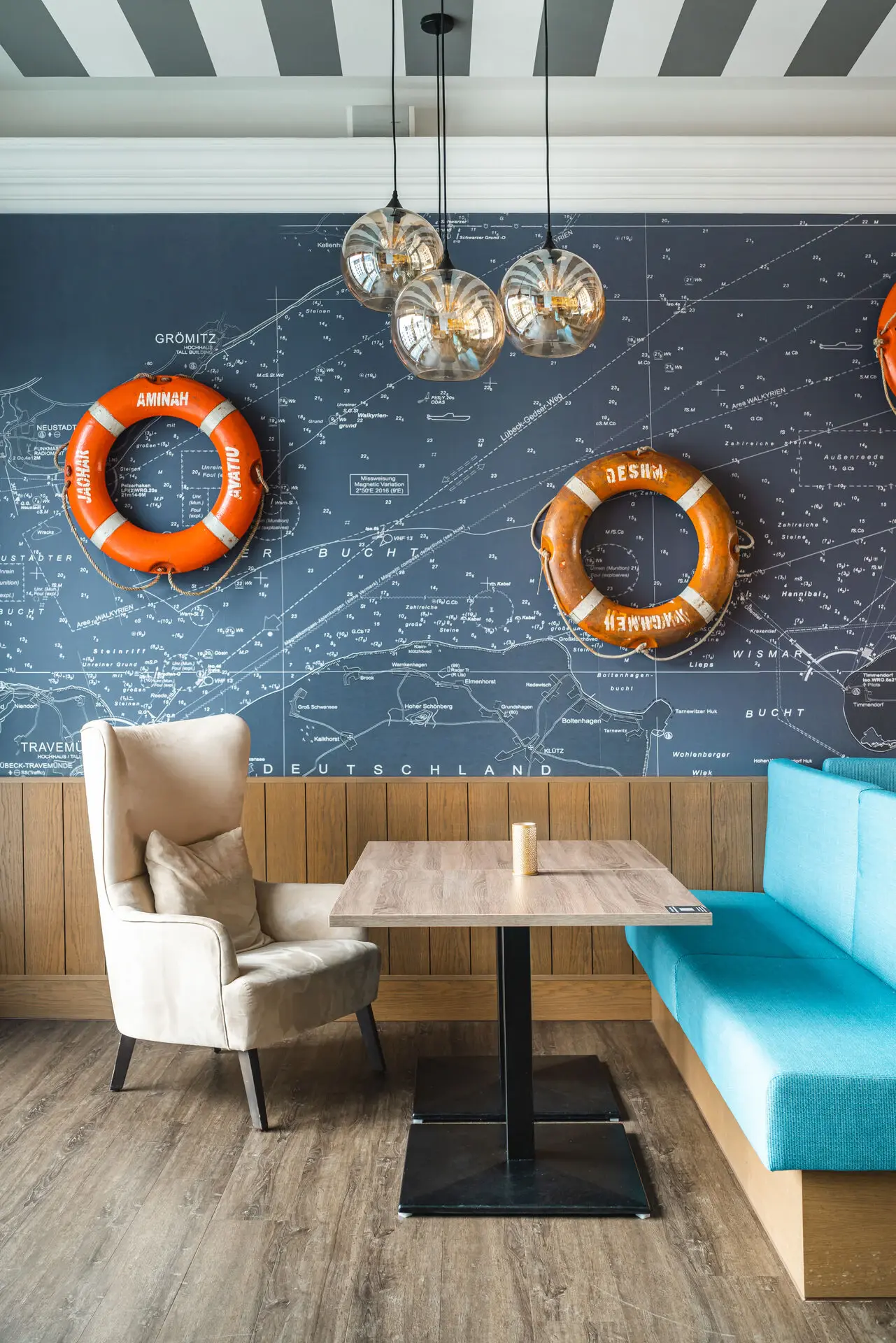 Ein Tisch und Stühle neben einem blauen Sofa, mit orangefarbenen Rettungsringen an der Wand