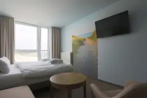 Doppelzimmer  Ein Zimmer mit einem Bett, einem Tisch und einem Fernseher.