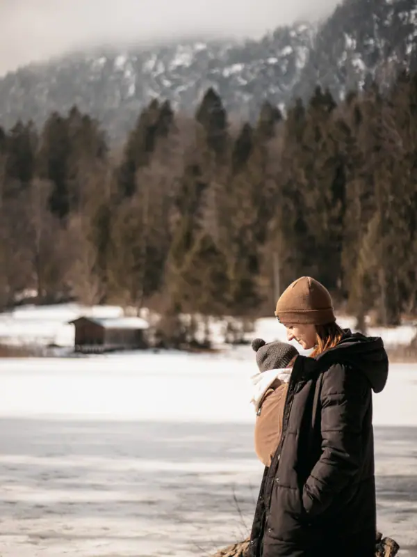 Eine Frau hält ein Baby in einem verschneiten Gebiet.