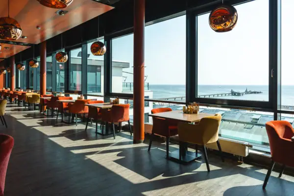 Restaurant Ein Raum mit Tischen und Stühlen, ein Fenster mit Blick auf den Ozean.