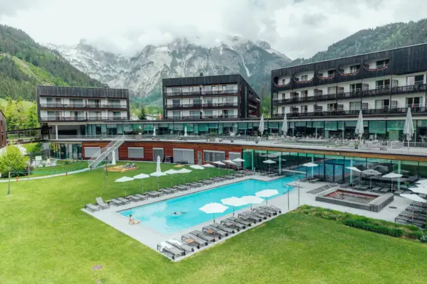 aja Bergresort Werfenweng Ein Außenpool in einem Hotel mit Rasen und Bergen im Hintergrund.