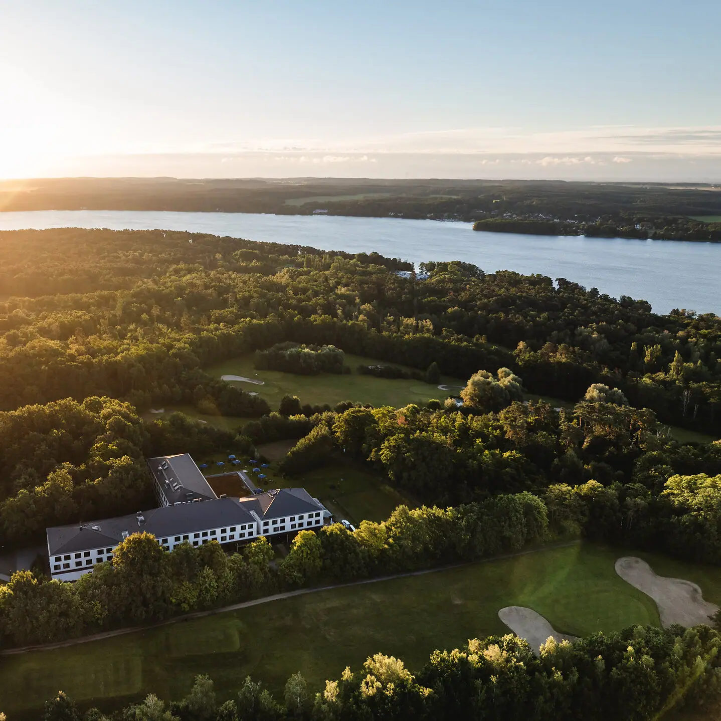 aja Bad Saarow Ein großes Gewässer mit einem Gebäude und Bäumen.