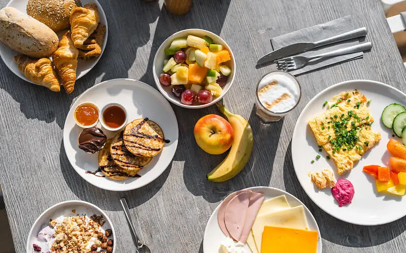 Frühstück Ein Tisch mit Tellern voller Speisen und Früchten.