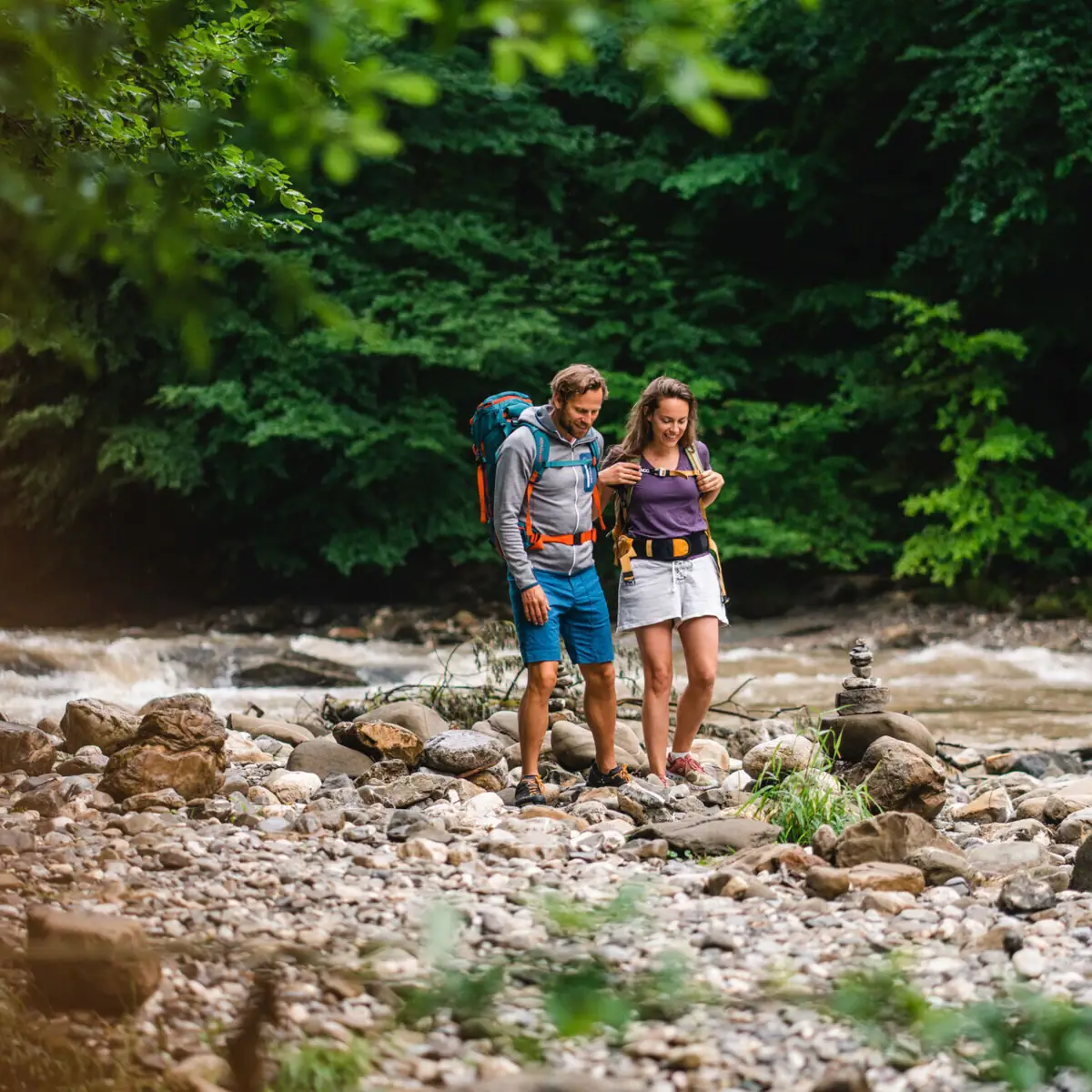 Ein Mann und eine Frau stehen auf Felsen an einem Fluss.