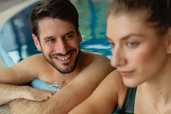 Ein Mann und eine Frau im Schwimmbecken lächeln.