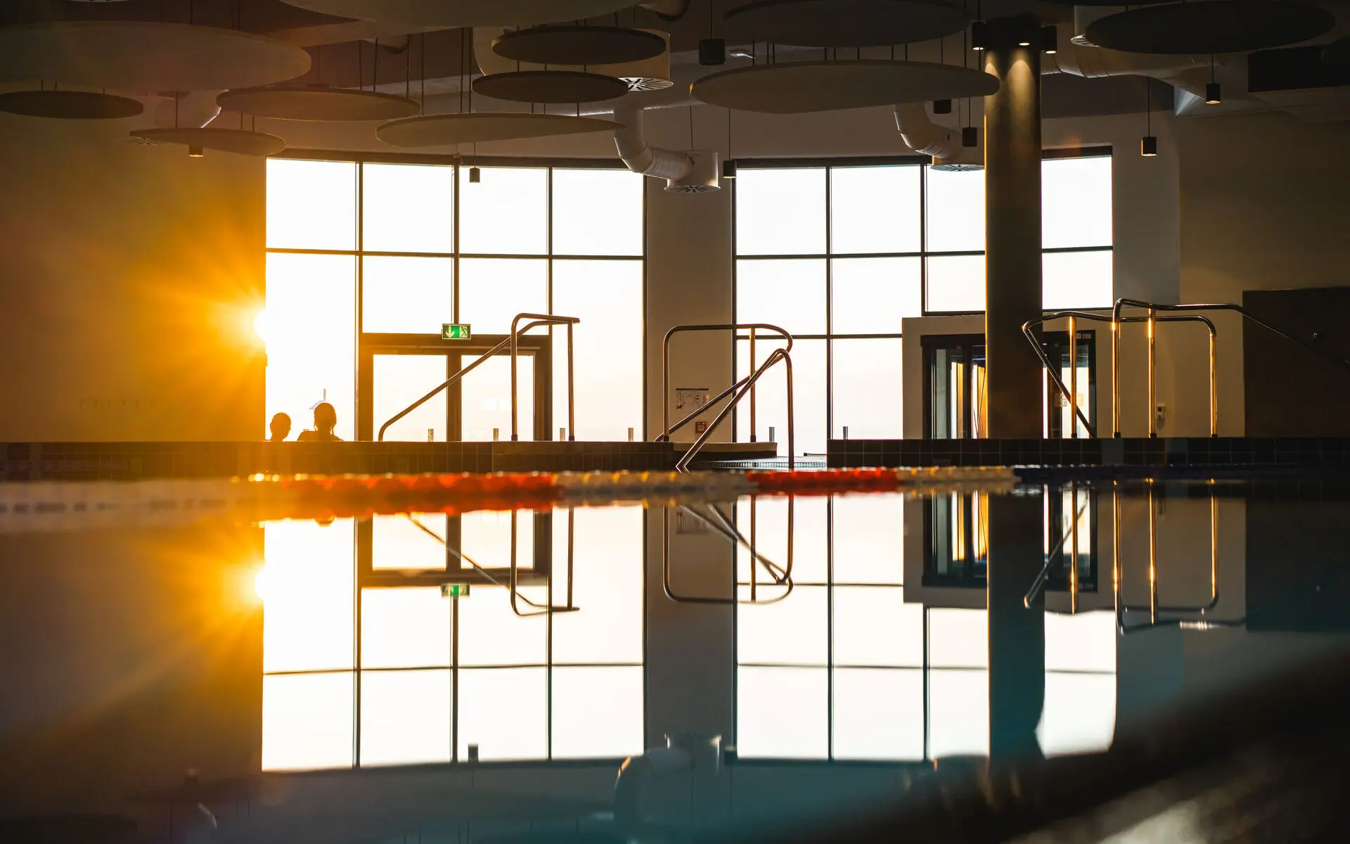 Swimming pool illuminated by natural light from a large window.