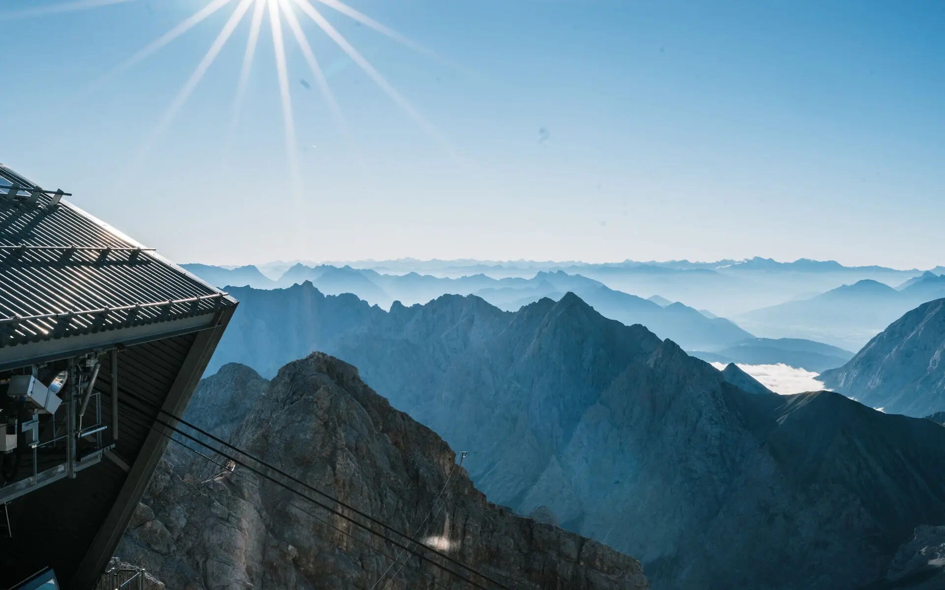 Berglandschaft mit Seilbahn und Sonnenschein.