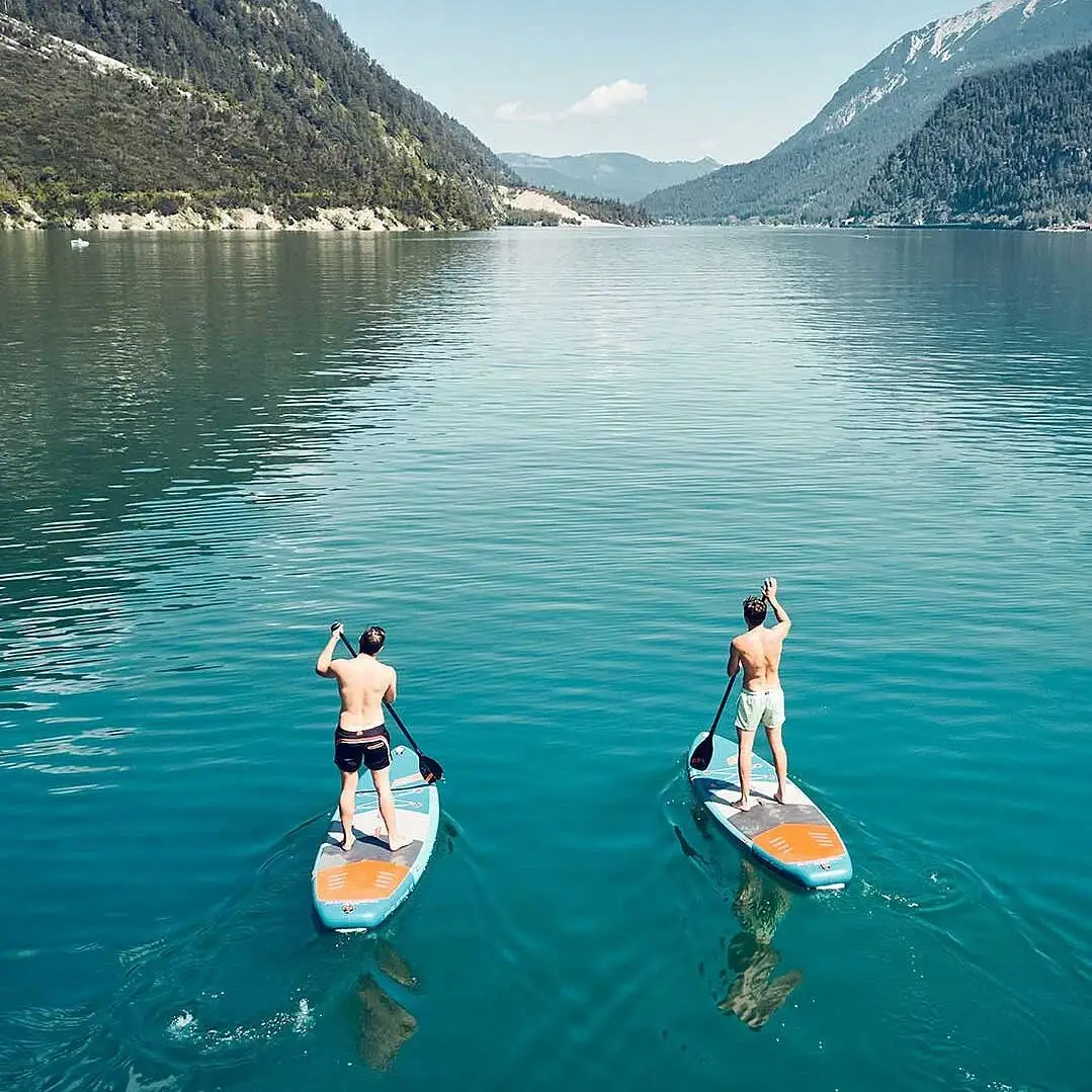 Zwei Männer auf Paddleboards auf einem See.