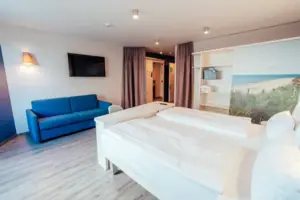 Ein Zimmer mit zwei Betten und einem blauen Sofa.