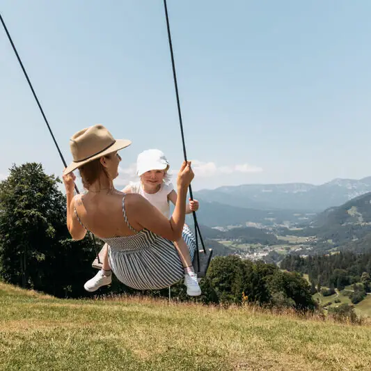Schaukel in Ruhpolding Eine Frau und ein Kind auf einer Schaukel im Freien.