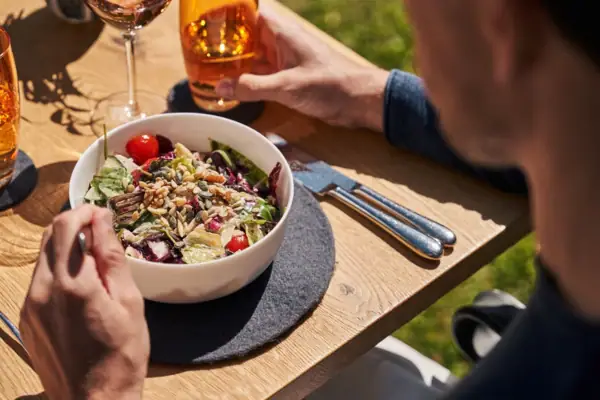 Salat Ein Mann isst einen Salat und trinkt Wein.