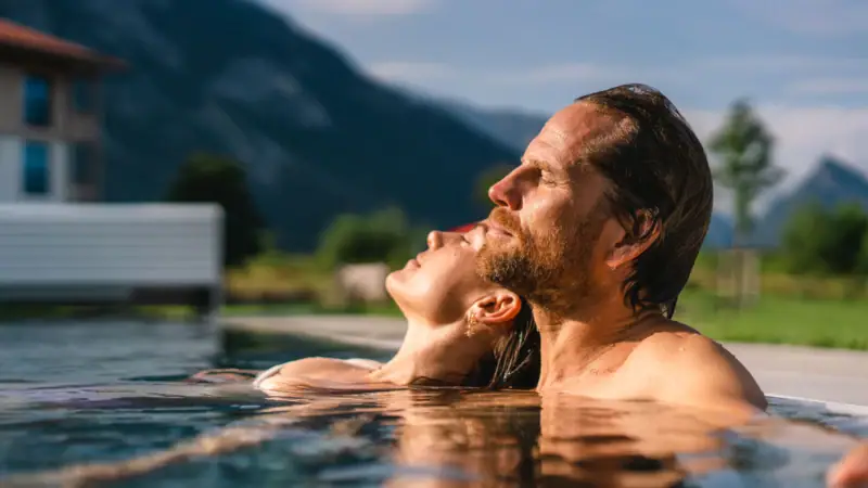 Außenpool im aja Ruhpolding Ein Mann und eine Frau in einem Pool.