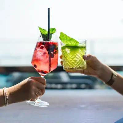 Zwei Hände halten Getränke mit Strohhalmen.