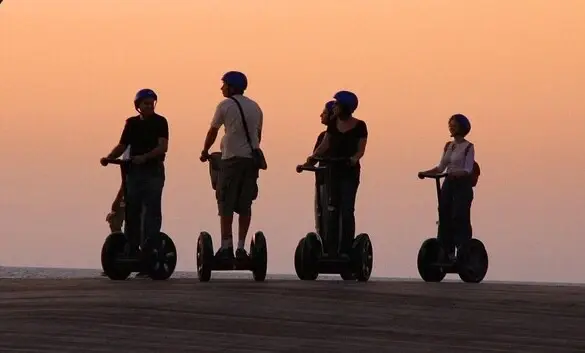 Group of people on Segways outdoors at sunset.