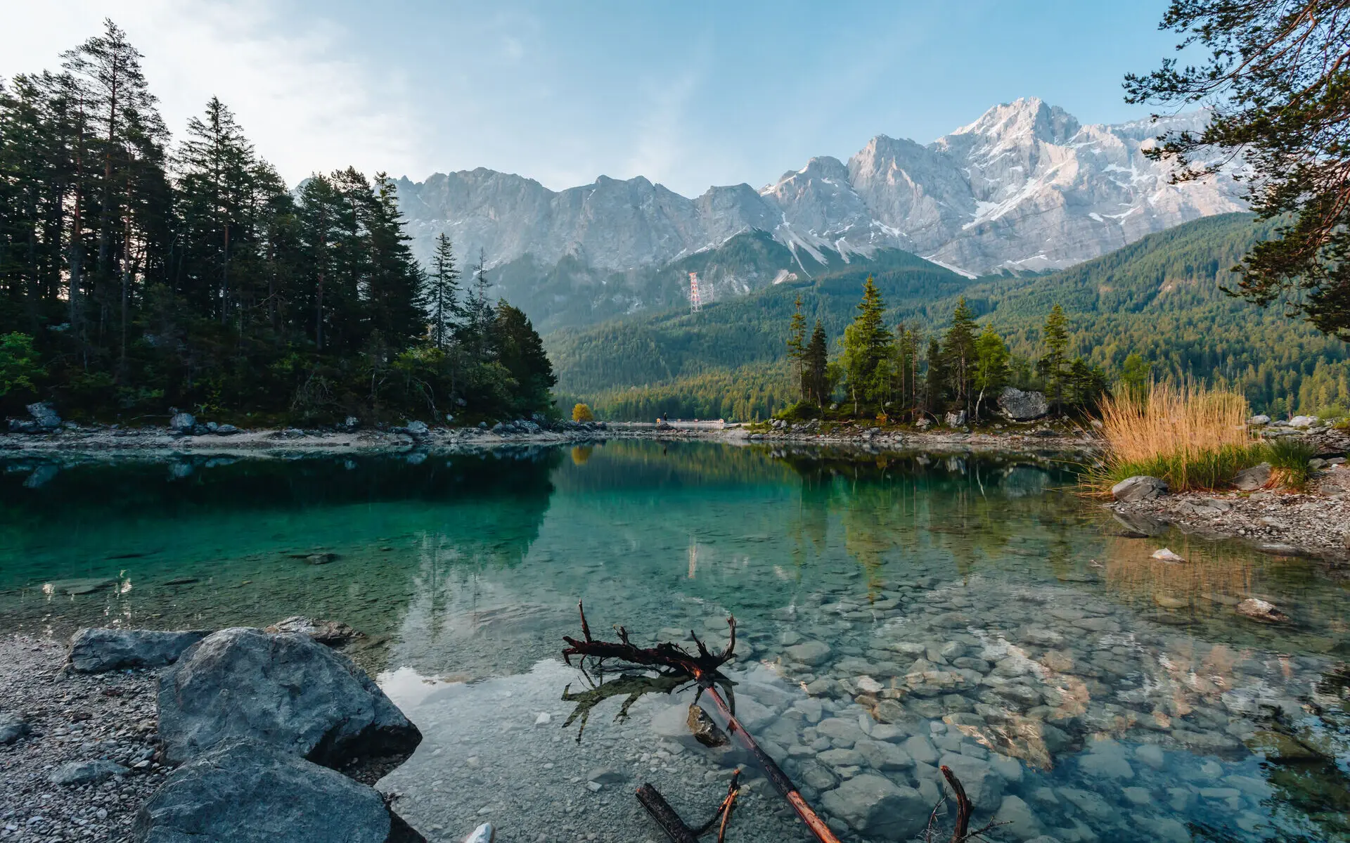 Der kristallklare Eibsee vom Ufer fotografiert mit einer Gebirgskette im Hintergrund.