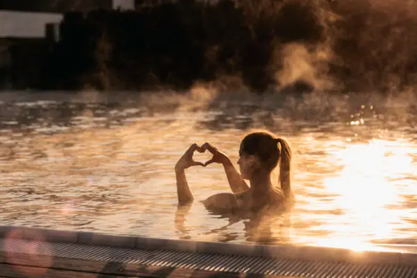 Eine Frau im Pool mit den Händen im Wasser.