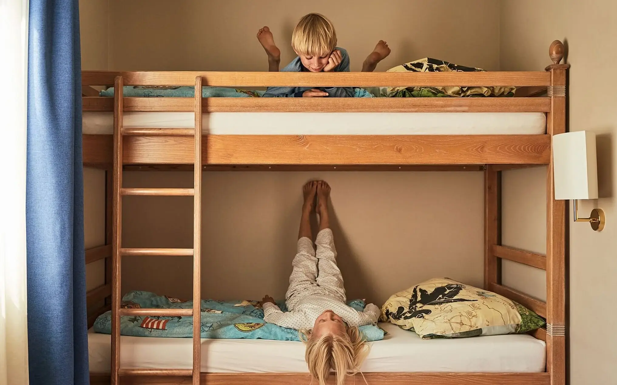 Ein Junge liegt oben auf einem Etagenbett neben einer Leiter.