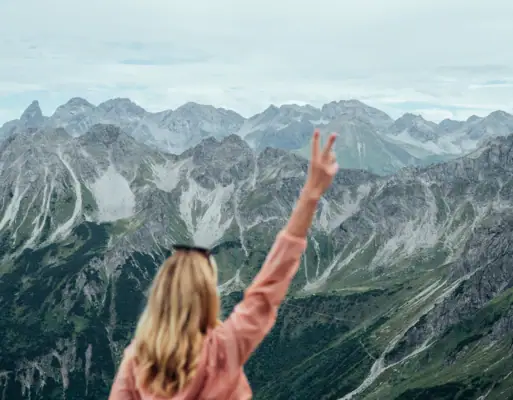 Eine Frau steht auf einem Berg und hebt die Hand.
