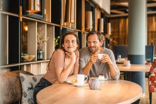 Ein Mann und eine Frau sitzen an einem Tisch mit Essen und Getränken.