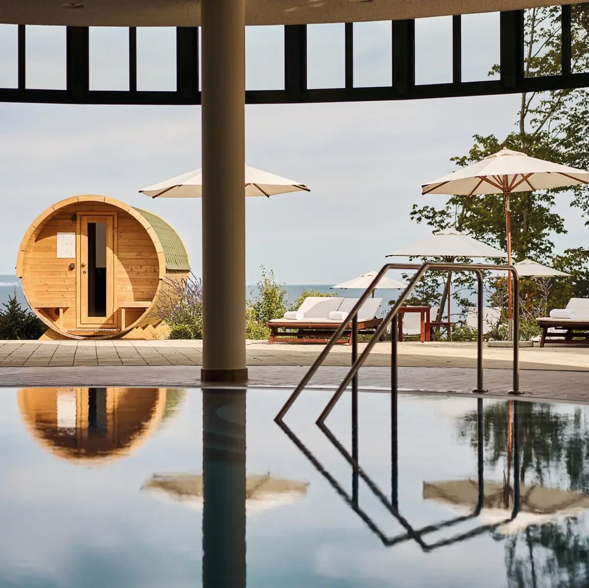 Innenpool mit Ausblick Ein Pool mit Sonnenschirmen und Stühlen im Freien.
