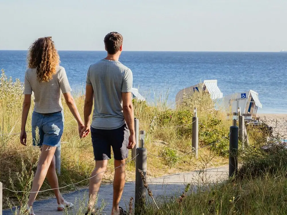 Ein Mann und eine Frau gehen auf einem Weg am Ozean entlang.