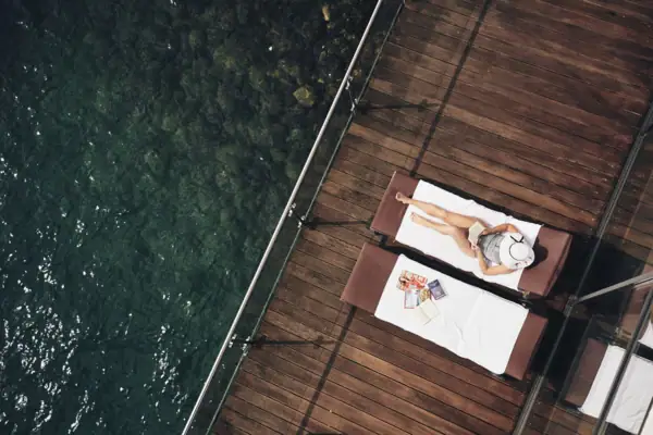 Eine Frau liegt auf einem Liegestuhl neben Wasser.