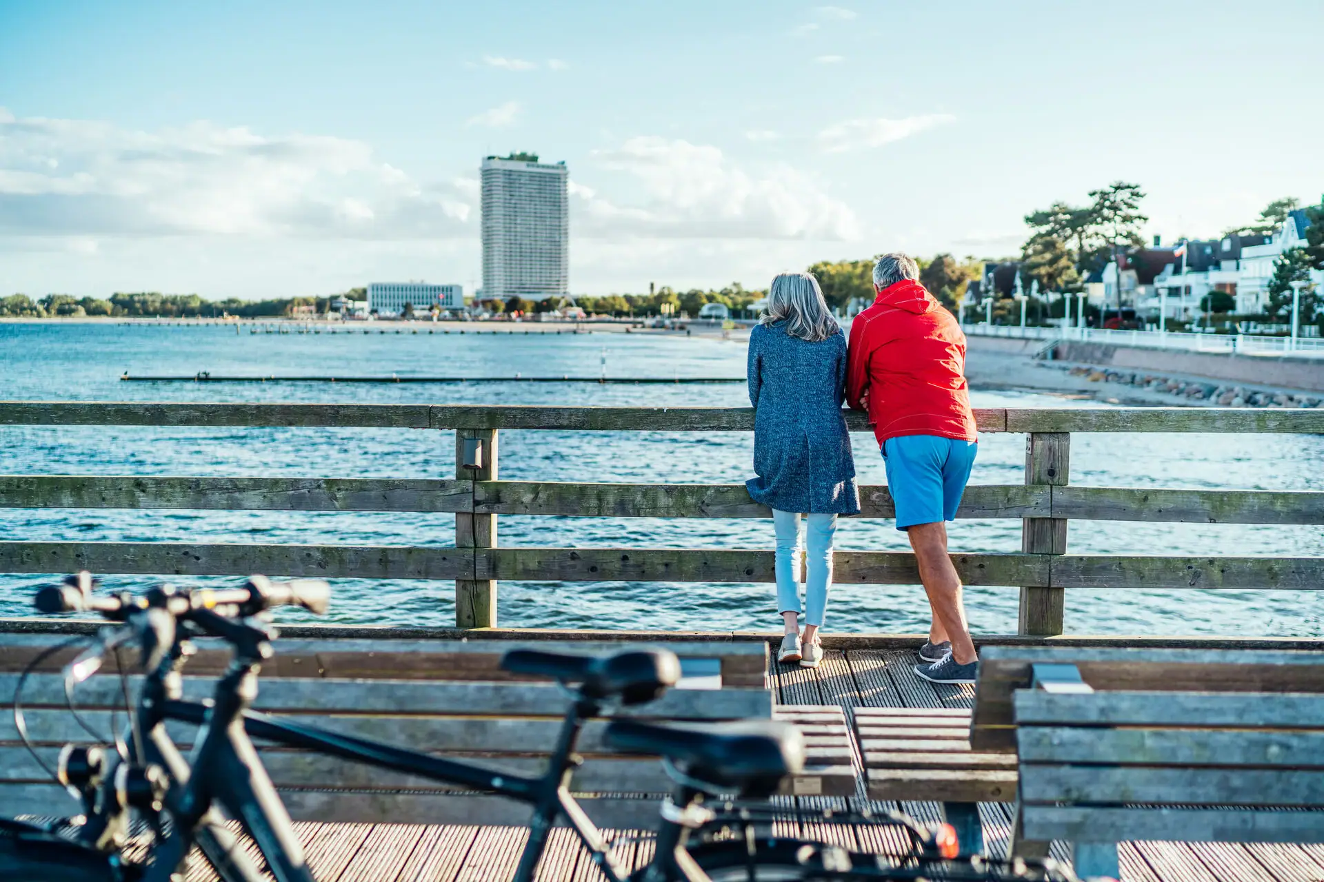 Ein Mann und eine Frau stehen auf einer Holzbrücke und blicken auf das Wasser.