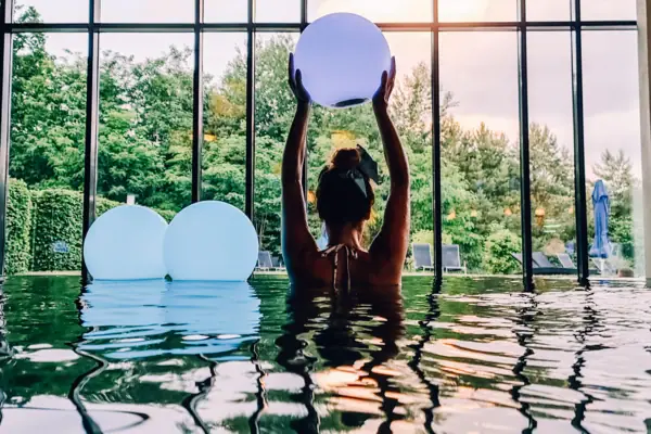 Innenpool Bad Saarow Eine Frau im Pool hält einen Ball.