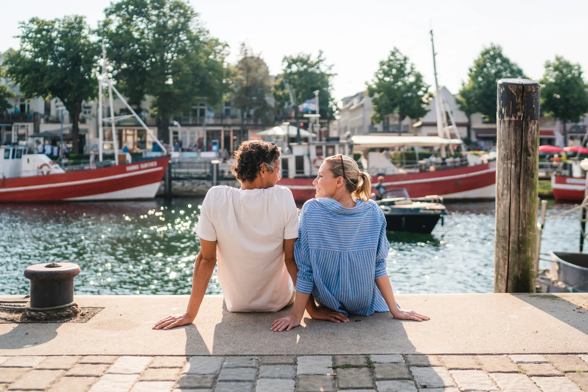 Alter Strom in Warnemünde Ein Mann und eine Frau sitzen auf einem Vorsprung und schauen sich an.