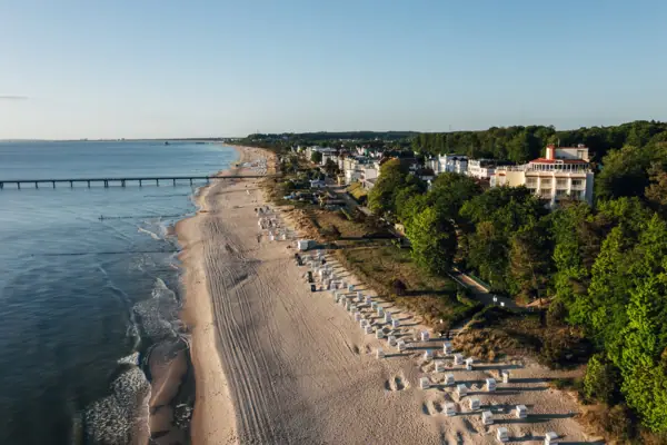 Strand mit Gebäuden und Bäumen im Vordergrund.