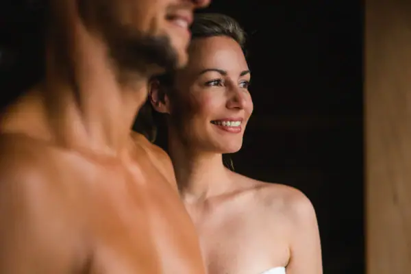 Ein Mann und eine Frau lächeln und stehen in einer Sauna.