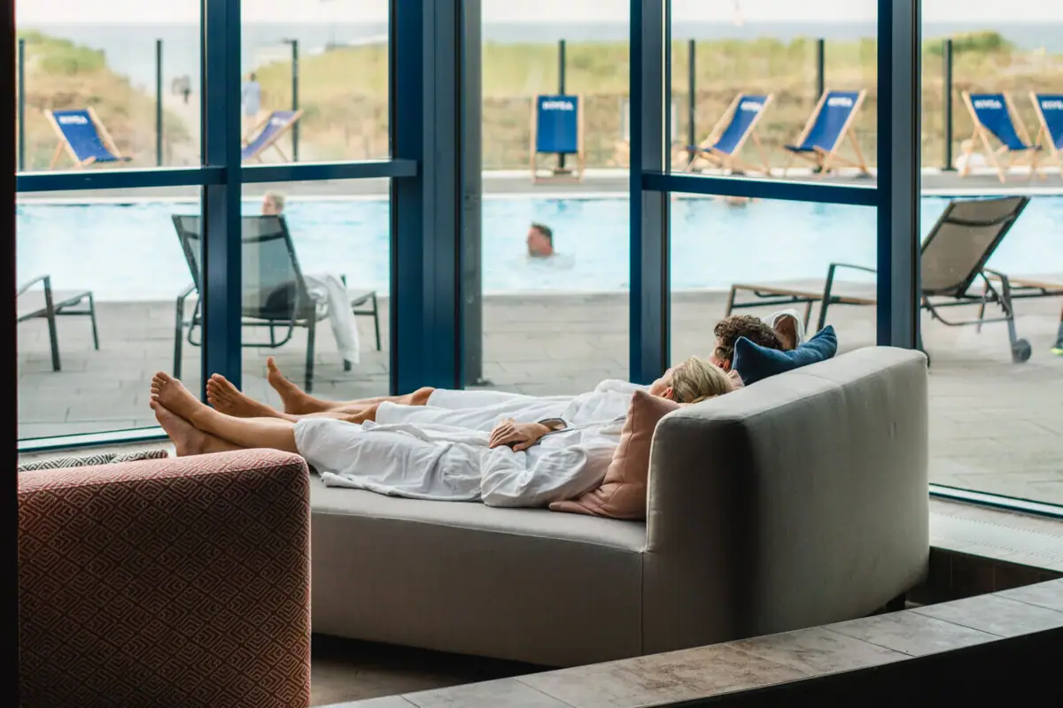 Eine Frau liegt auf einer Couch neben einem Pool.