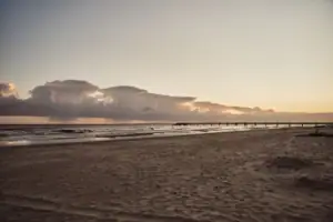 Strand Bansin Ein Strand mit einem Pier und Wasser im Vordergrund.