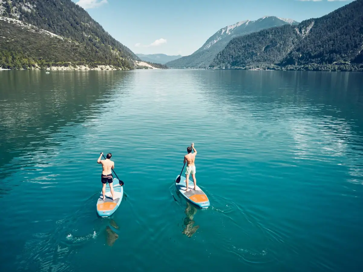 SUP auf dem Achensee Zwei Männer auf Paddleboards auf einem See.