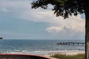 Ausblick Ein Pier auf dem Wasser unter wolkigem Himmel.