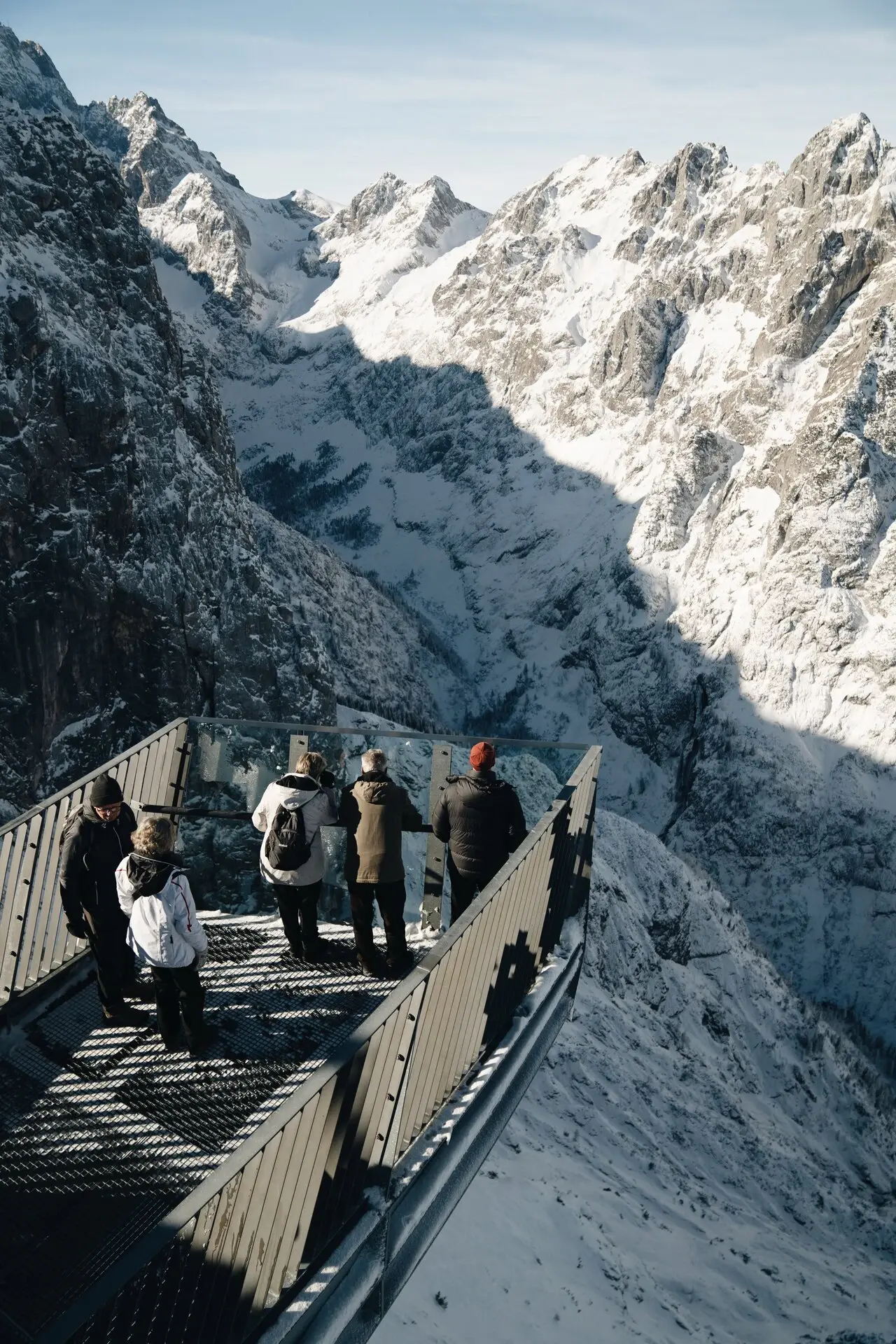 Gruppe von Personen auf der Aussichtsplattform AlpspiX über verschneiten Bergen.