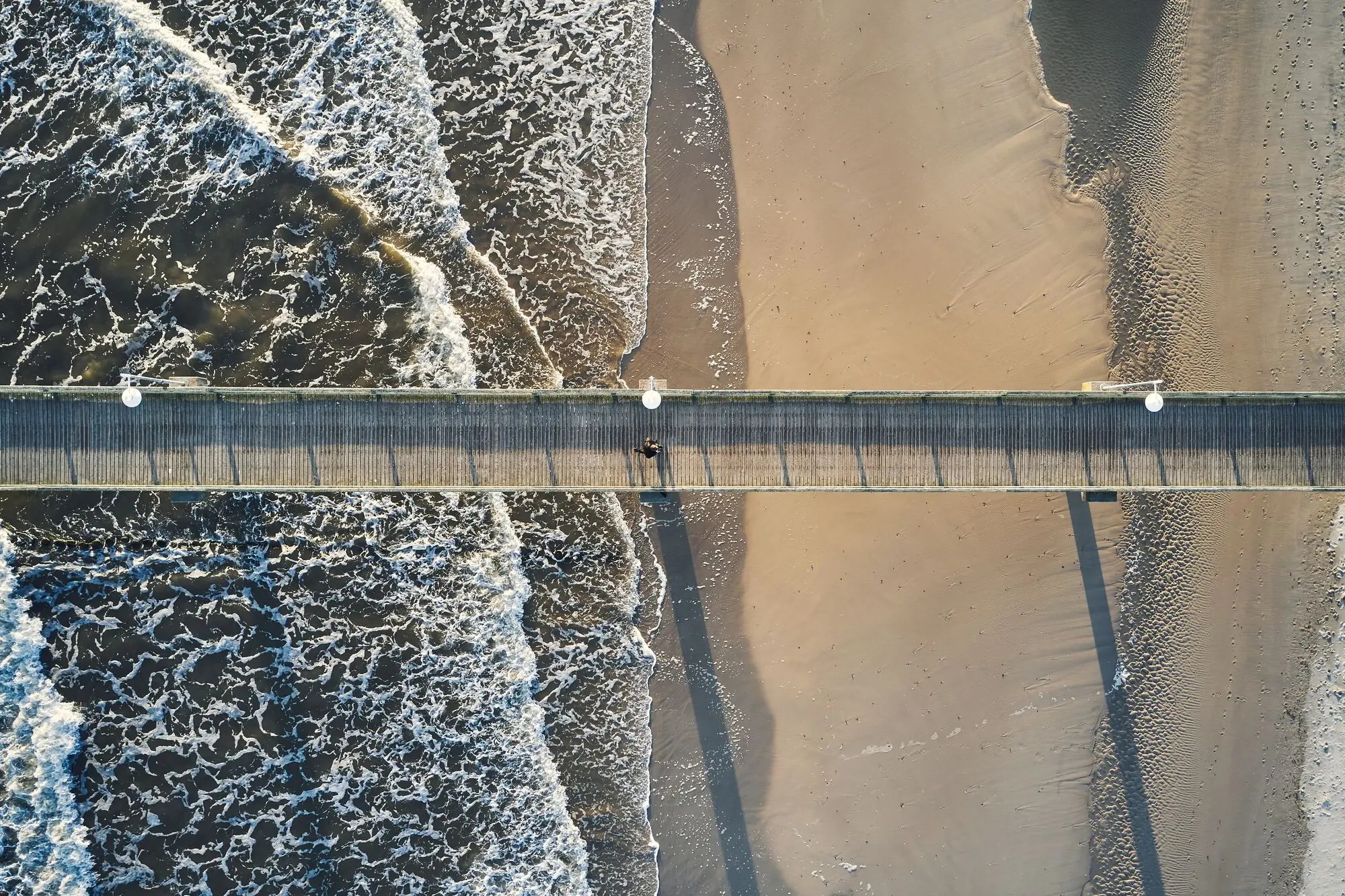 Eine Seebrücke über dem Meer und dem Strand.