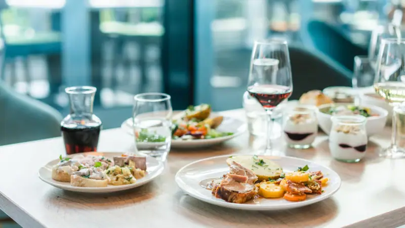 Abendessen Ein Tisch mit Tellern voller Speisen und Weingläsern.